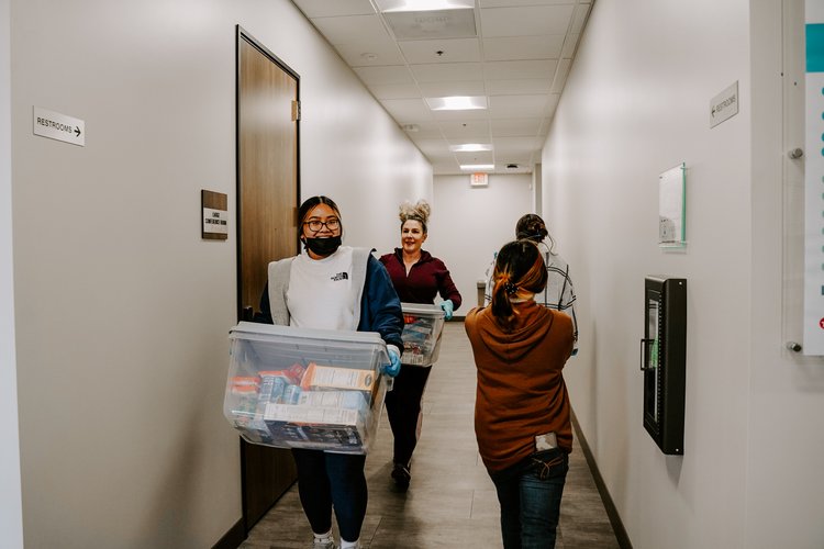 Multiple women holding bins at a Thanksgiving food drive